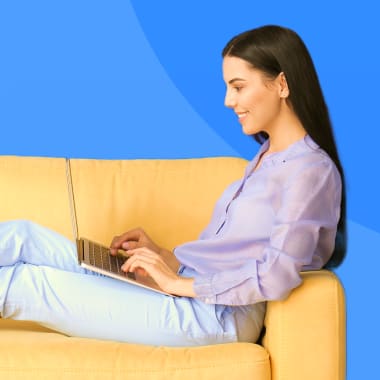 a woman sitting on a armchair and typing on a computer