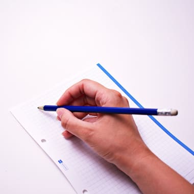 a hand holding a pencil over a sheet of paper