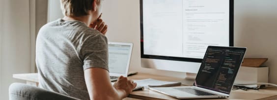 young man sitting behind the multiple screens working on Knowledge Management System