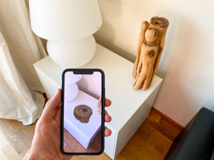 a phone with the AR app showing a wooden object in the room