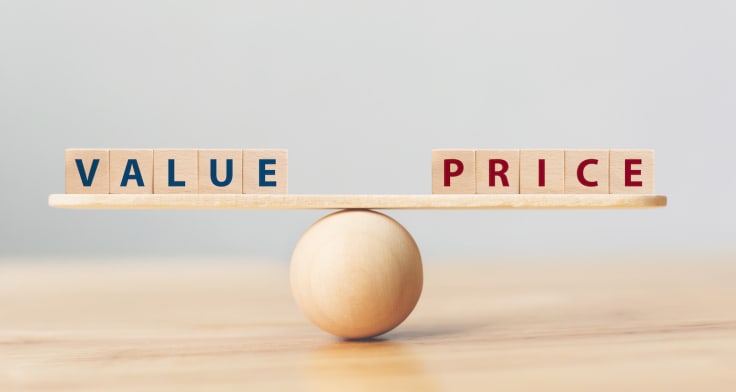 Wooden seesaw scale empty on wooden sphere on wood table with wording VALUE and PRICE balancing