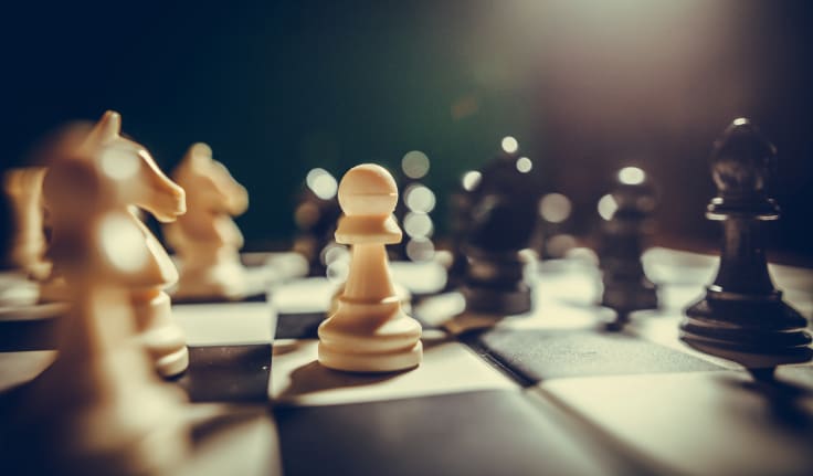 Image of the white and black pieces on a chess board, with shallow depth of field.