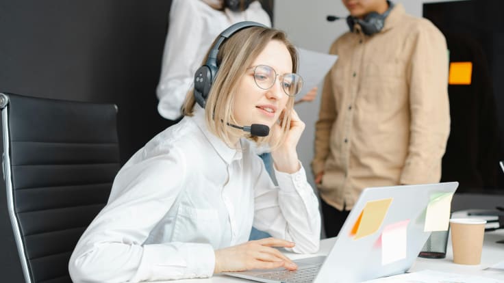 a helpdesk agent speaking with a client thriugh headphones