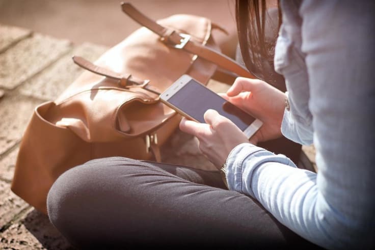 Girl sitting holding a phone texting sms