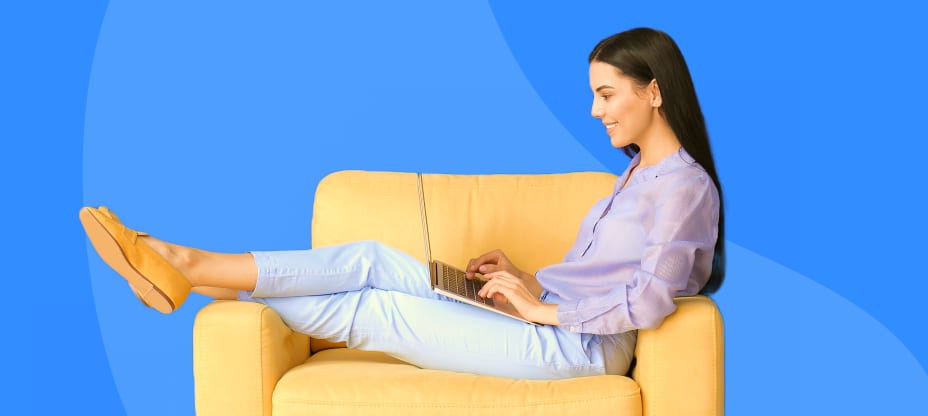 a woman sitting on a armchair and typing on a computer