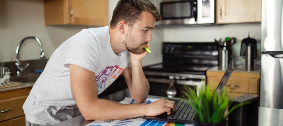 a man standing in front of a computer in kitchen