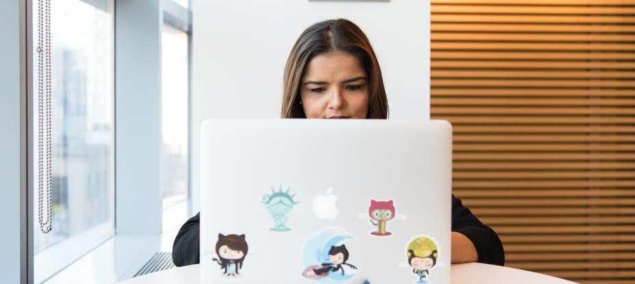 a woman sitting in front of a macbook