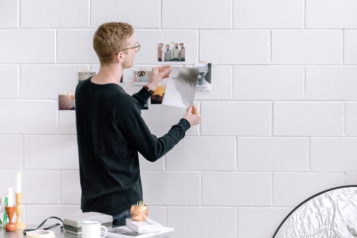 man sticking photos on wall