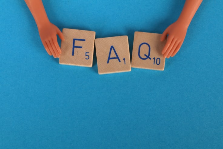 Hands putting blocks with the FAQ letters on a blue background