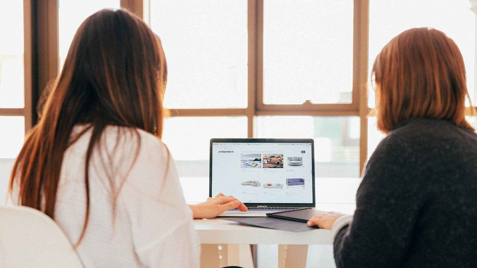 Zwei Frauen schauen auf einen Laptop