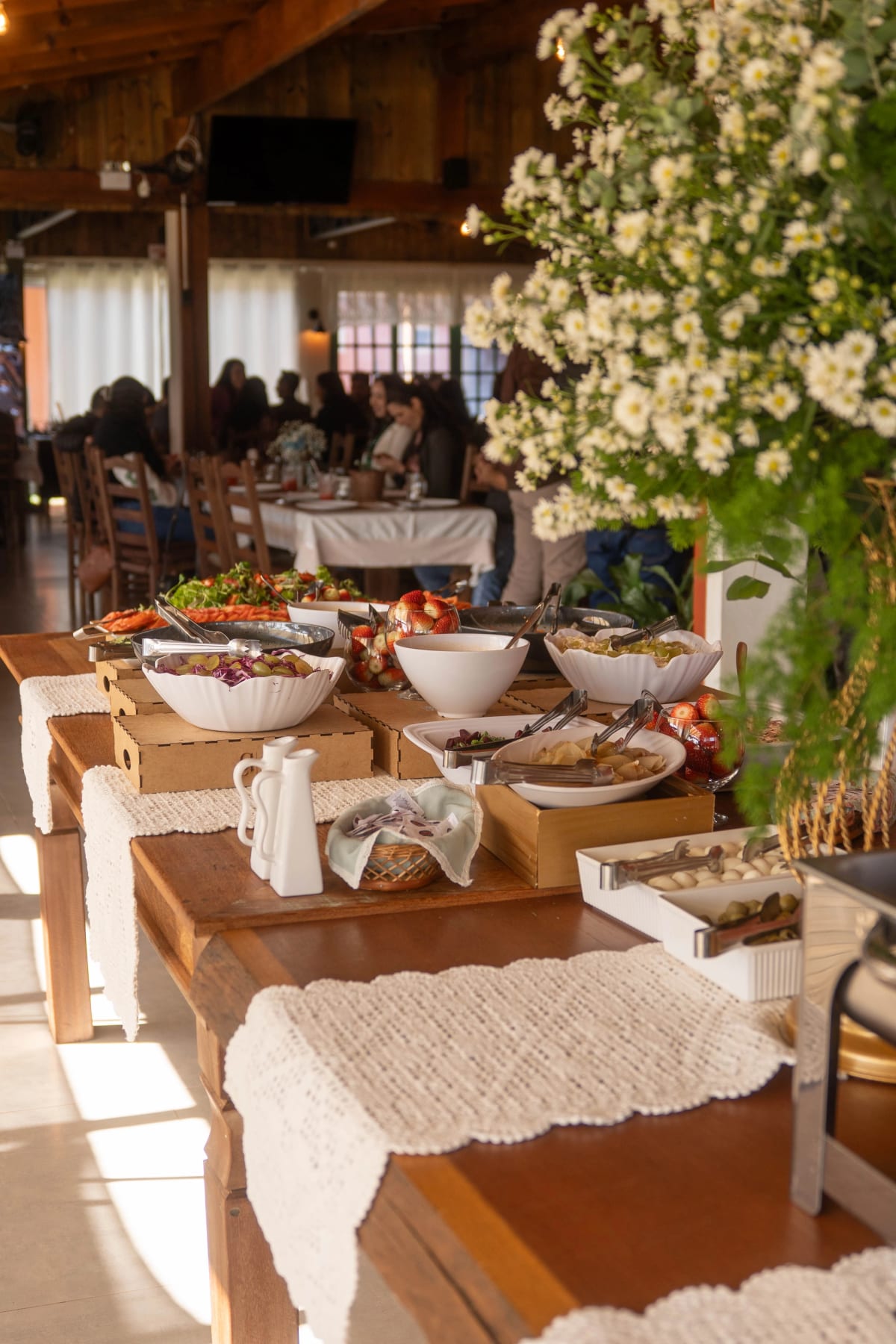 Mesa de buffet montada com saladas e arranjos de flores no salão