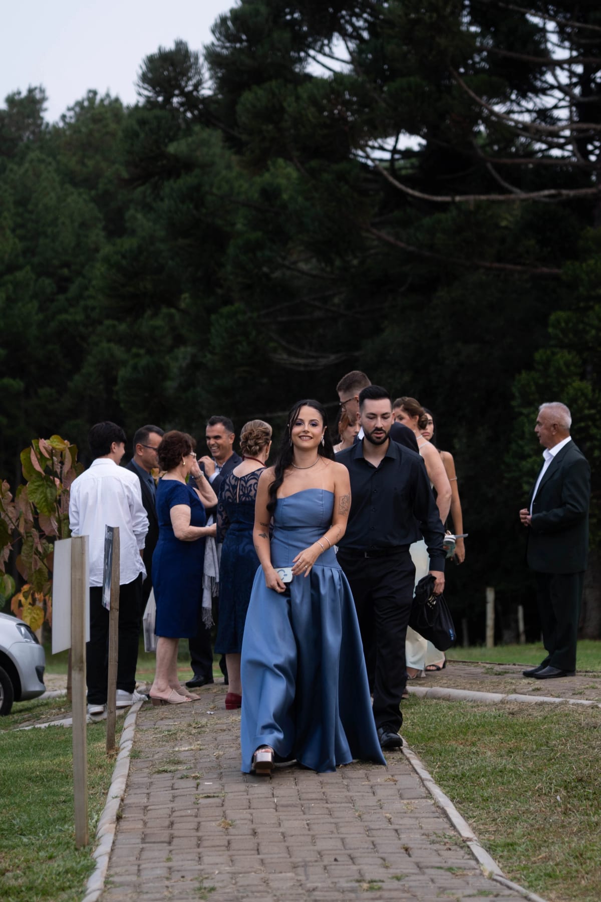 Convidada de vestido azul caminhando com outros convidados pelo caminho de pedras da Casa França