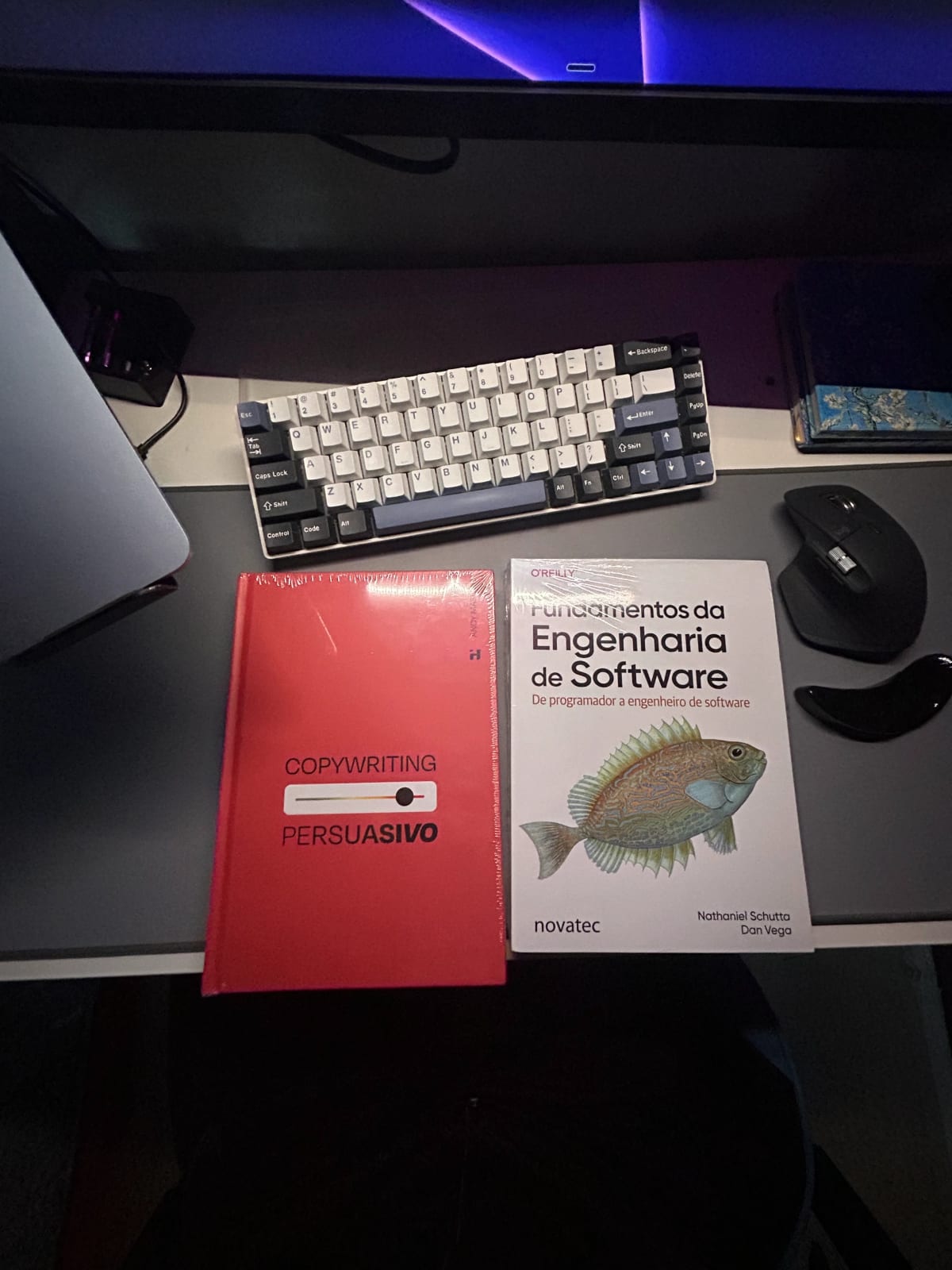 Mesa de trabalho com teclado, mouse e livros de engenharia de software