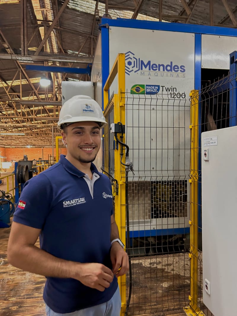 Rafael Gois ao lado de máquina industrial da Mendes Máquinas, no chão de fábrica