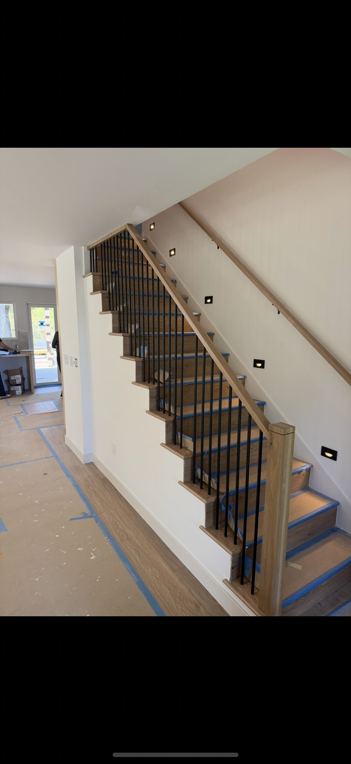 New construction staircase with oak handrail and black metal balusters