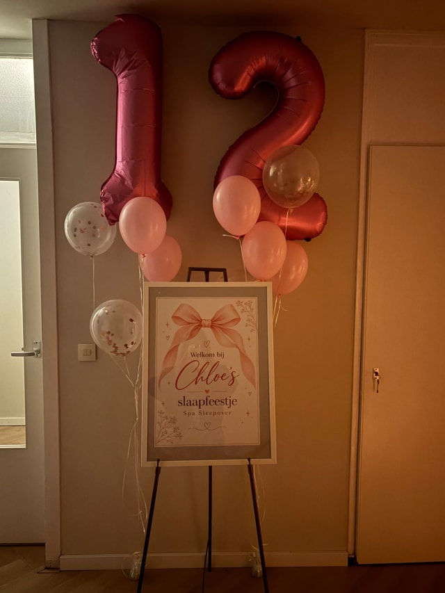 Welkomstbord voor een slaapfeestje op een ezel met roze cijferballonnen
