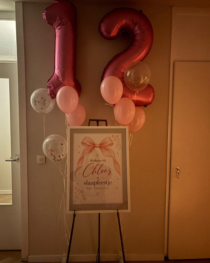 Welkomstbord voor een slaapfeestje op een ezel, met roze cijferballonnen 12