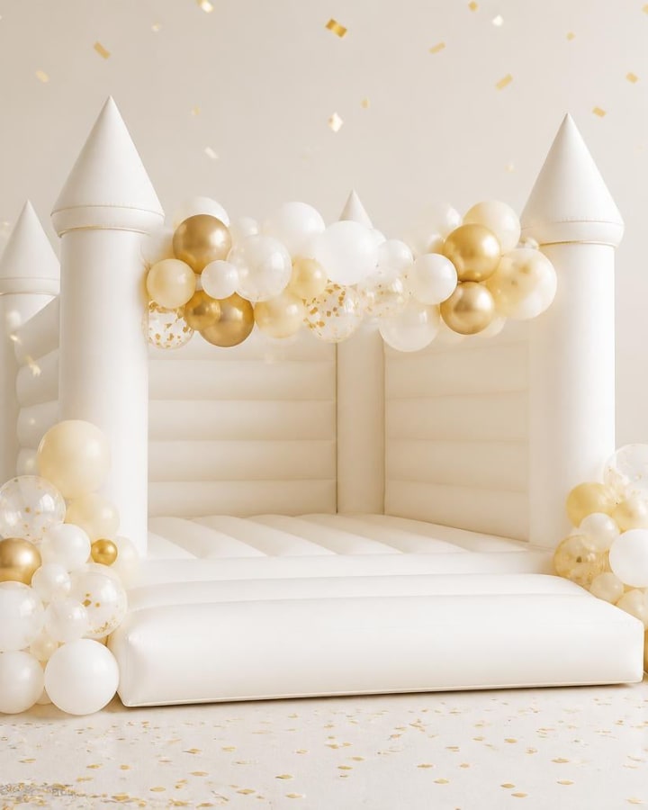 Wit springkussen in kasteelvorm met crème en gouden ballonnen