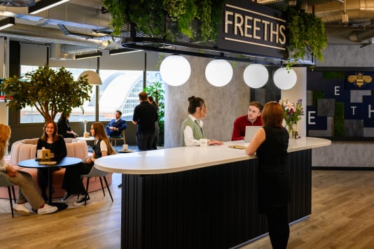 colleagues stood aroundtable in Freeths Manchester office chatting