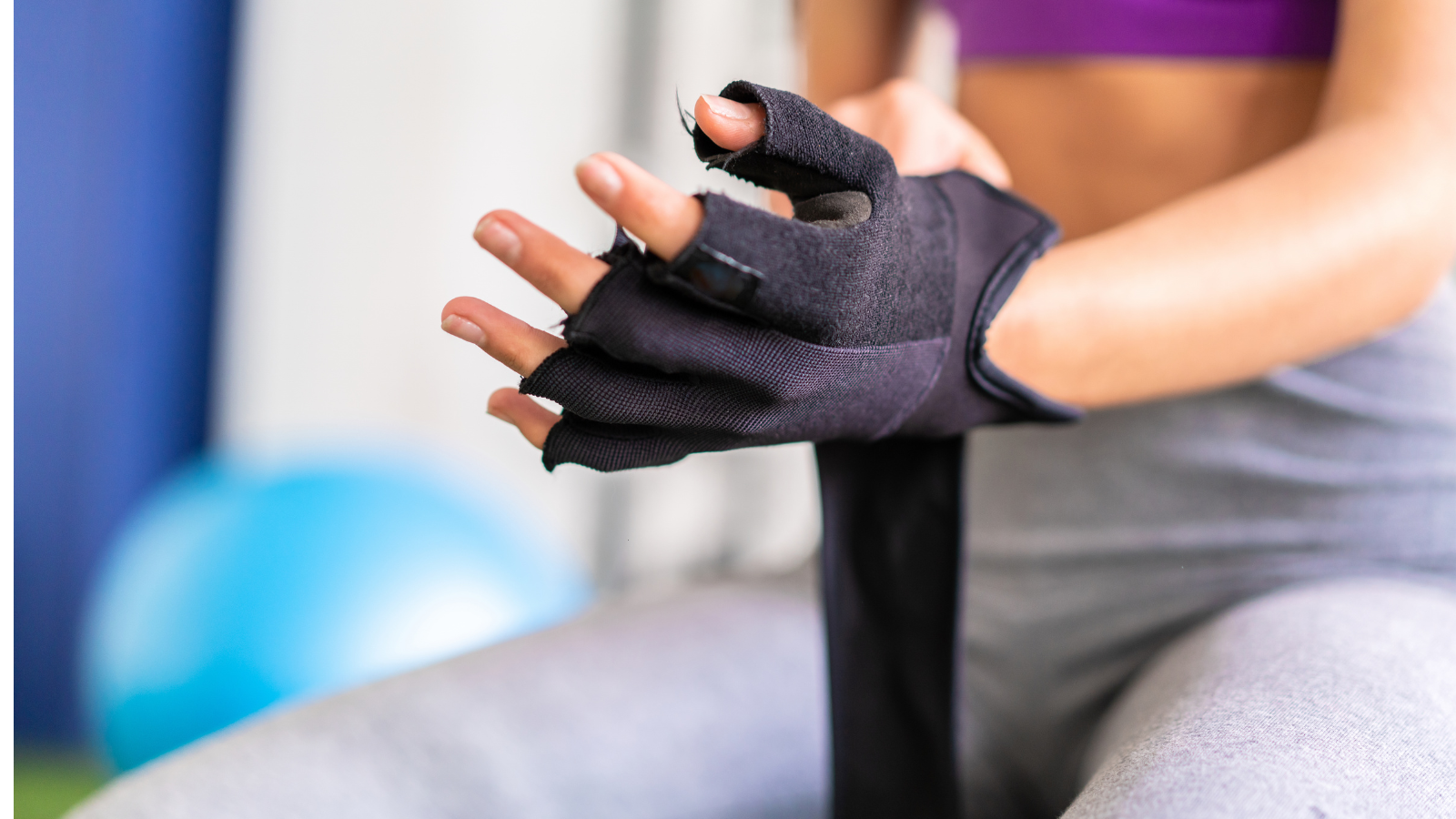 Woman adjusting the wrist strap on a fingerless training glove before a workout
