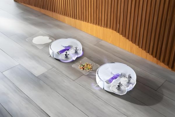 Two robotic vacuums cleaning a hardwood floor, demonstrating creative robot vacuum hacks for efficient housekeeping.