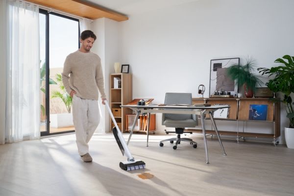 A man using innovative vacuum cleaners to effortlessly clean a modern living space with wooden floors and stylish decor.