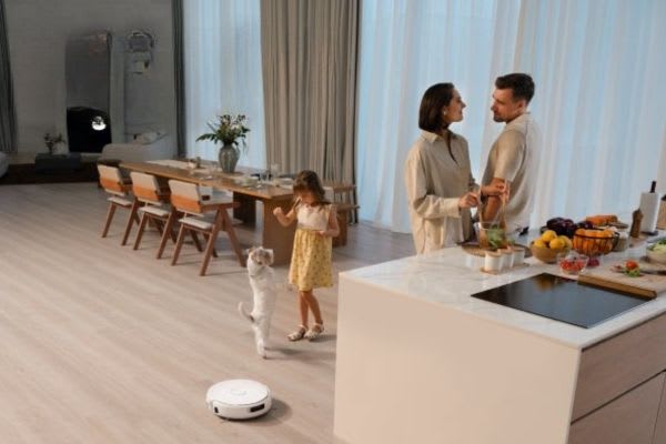 A family enjoys time together in a modern kitchen while a vacuum robot automatically cleans, showing when to use brush roll on vacuum.