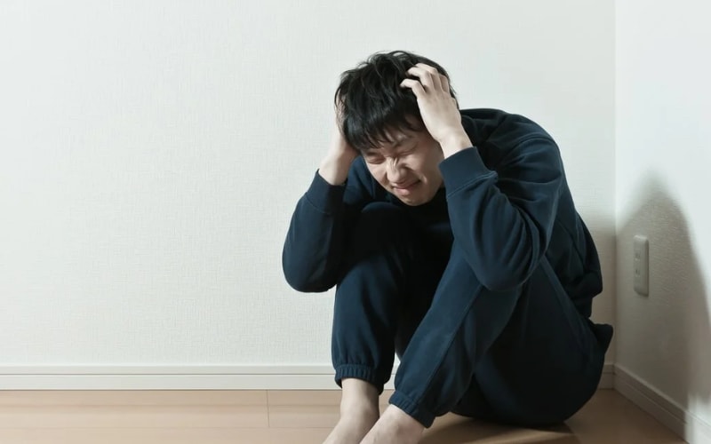 家が汚い環境でストレスを感じ、頭を抱えている男性の姿が映っています。