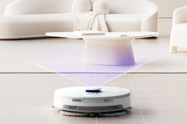 自動掃除機が部屋をきれいにする方法を示しています。白いソファとテーブルとともに掃除中です。
