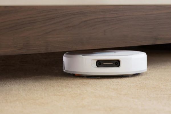 A robot vacuum partially stuck under furniture, questioning if robot vacuums can go over threshold obstacles effectively.