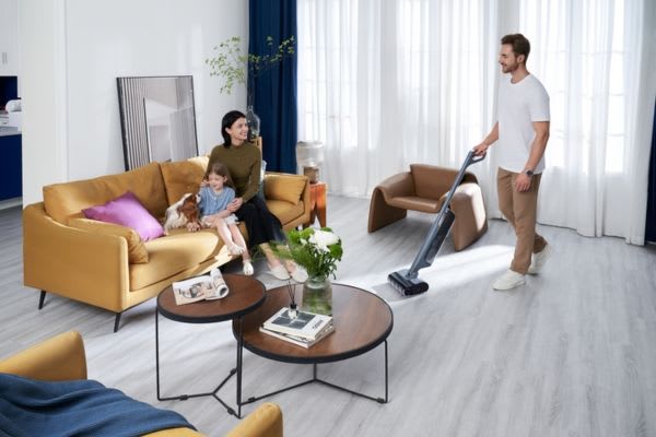 A man uses a vacuum cleaner in a modern living room, highlighting the efficiency of dust mop vs vacuum cleaning methods.