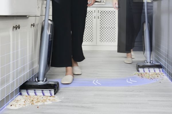 A person using a vacuum and another with a dust mop, highlighting the differences between dust mop vs vacuum for cleaning.