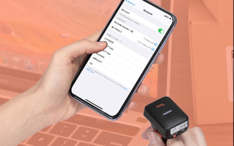 A hand holds a smartphone displaying Bluetooth settings while connecting to scanner accessories for seamless usage.