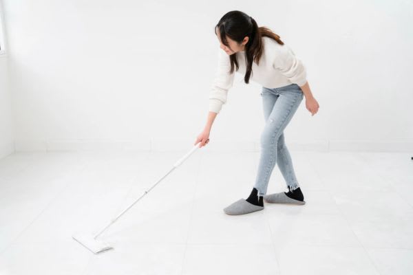 女性が掃除道具を使って部屋の床を掃除し、家事スキルを向上させています。