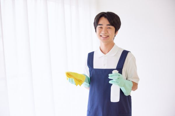 秋の大掃除を楽しむ男性が、掃除用具を手に笑顔で立っています。清潔感のある空間が広がっています。