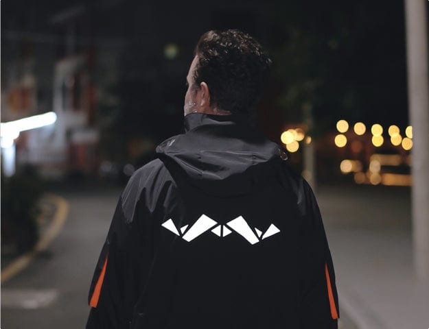 A person wearing a stylish jacket walks down a street at night, showcasing the debate of coat vs jacket in fashion.