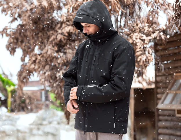 A man wearing a black jacket in the snow, showcasing the comfort and style comparison of parka vs jacket.
