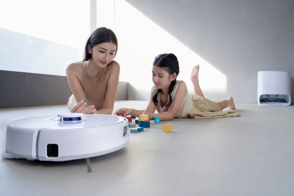 母親と子供が遊びながら、掃除ロボットが家の掃除をし、ストレス解消を楽しんでいる様子。