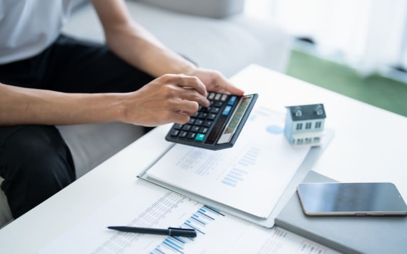 A person calculates financial data with a calculator, analyzing trends related to the barcode scanner market.