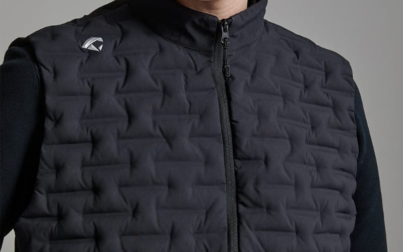 A close-up of a person wearing a black vest, highlighting the differences between softshell vs fleece materials.