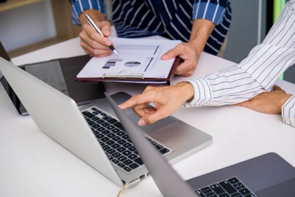 ビジネスミーティングで、パソコンと書類を使いながら、amazonの秋セールについて議論しています。