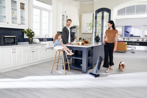 A family enjoys time together in a bright kitchen while house cleaning robots simplify their cleaning tasks.