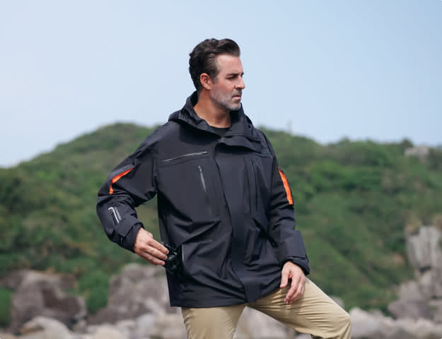 A man in a waterproof jacket poses outdoors, illustrating why cotton is bad for hiking due to moisture retention.