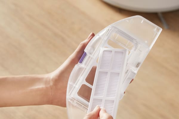 A close-up of a hand holding a HEPA vacuum cleaner filter, ready for replacement or maintenance.