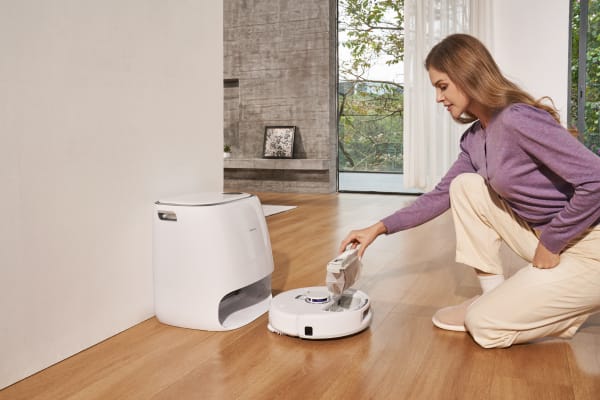 A person uses a HEPA vacuum cleaner while kneeling on a wooden floor in a modern living space.