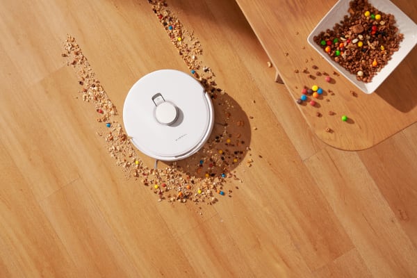 A robotic vacuum cleans up scattered food crumbs, showcasing what is a good suction power for vacuum cleaner.