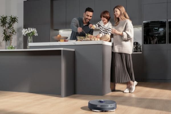 A family enjoys cooking together in a modern kitchen, while a robot vacuum showcases mapping vs no mapping technology.