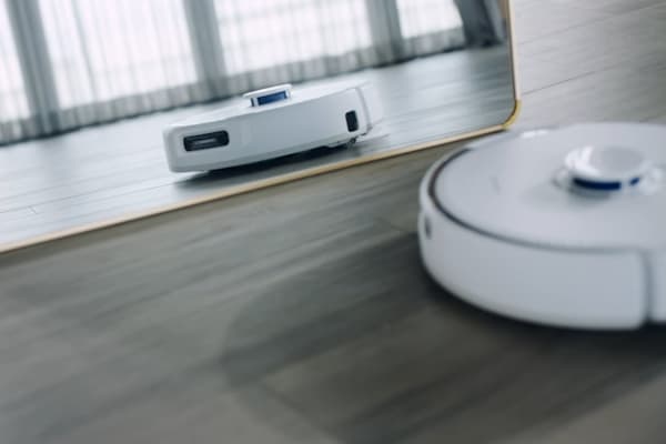 A robot vacuum glides across the floor, reflecting in a mirror while ensuring household privacy.