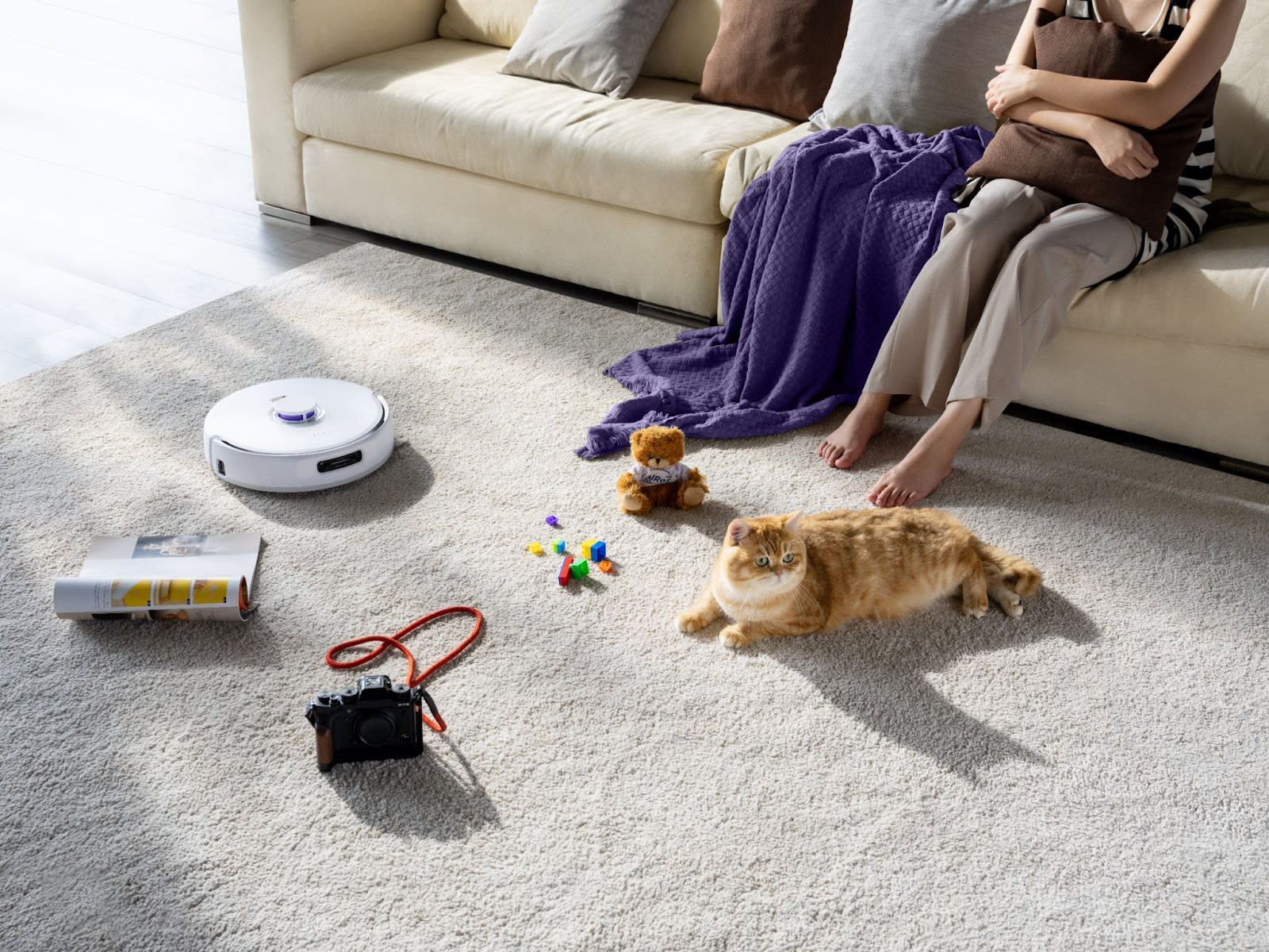 A cozy living room scene featuring a cat, robot vacuum, and toys, showcasing flooring compatibility.