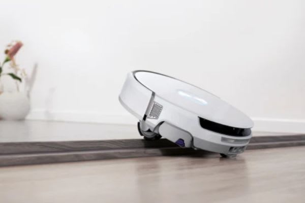 A robot vacuum navigating a threshold, illustrating the question: can robot vacuums go over threshold?